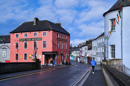 Kilkenny, Ireland - March 23, 2023:  Colorful pubs and hotels on a main street in Kilkenny, Ireland, with people walking on the sidewalk