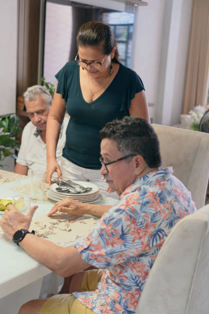 latin family cleaning up after lunch. - domestic kitchen senior adult built structure candid imagens e fotografias de stock