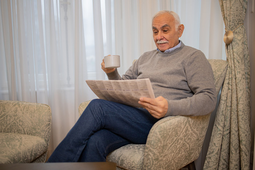 Young man and an elderly woman sitting in armchairs and reading newspapers isolated on white background