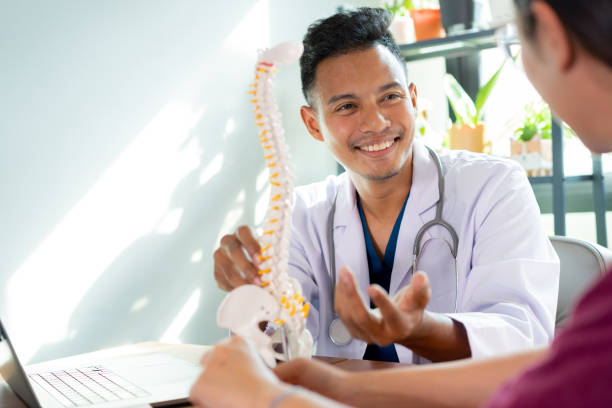 physiothérapeute en gros plan expliquer sur le squelette humain au bas du dos pour conseiller et consulter le patient au traitement au bureau pour le concept de soins de santé - doctor patient chiropractic adjustment communication photos et images de collection