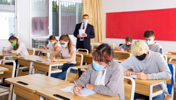 istock Schoolgirl wearing protective mask working in class 1498557733