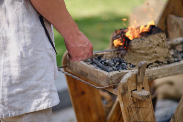 A blacksmith in a forge forges metal. Blacksmithing in retro style outdoors