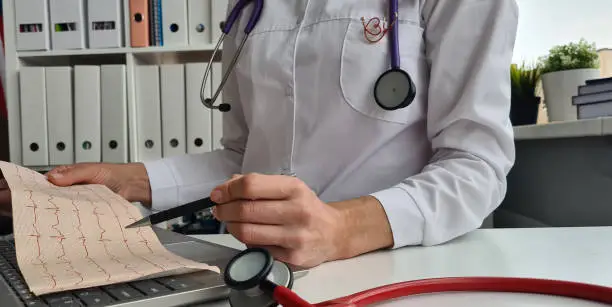 Photo of Cardiologist examines cardiogram and models of artificial heart