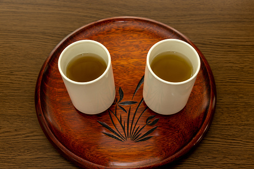 Japanese teacups with green tea on the wooden round tray