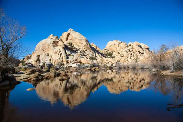 Stunning reflections of the dramatic rock formations in the still water of Barker Dam in Joshua Tree National Park