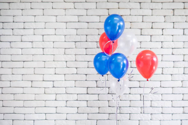istock Balloons red, blue, and white against a white brick wall in the background. 1498569788