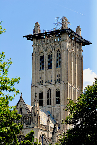 Washington, DC, USA - June 5, 2023: The tower of the Cathedral Church of Saint Peter and Saint Paul in the City and Diocese of Washington—better known as the Washington National Cathedral—undergoing repairs on a sunny Spring afternoon.