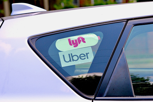 Fairfax, Virginia, USA - June 5, 2023: Close-up of Lyft and Uber stickers inside a car window driving through George Mason University’s main campus.