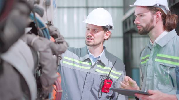 istock Team maintenance engineer working with robotic arm in factory. Industry of robot programming installing for automated manufacturing technology. Mechanical engineer check the quality of the machine parts according to the program on tablet. 1498581542