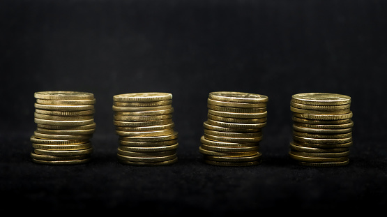 arranged stacks of several gold coins isolated in a black background