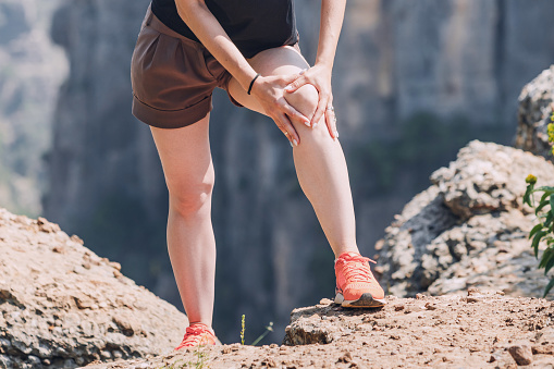 Una joven excursionista experimentó un dolor agudo en la articulación de la rodilla durante el senderismo y la caminata en las montañas photo