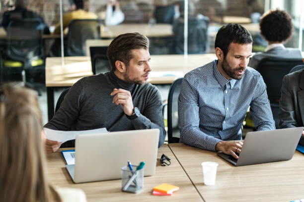 istock Mid adult businessmen working on computer at full office. 1498602250