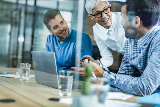 istock Happy business team talking while working on laptop in the office. 1498603533