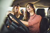 Cheerful female friends going on a road trip in a car.