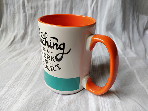 A photo of a glass mug for coffee or tea with white orange blue color