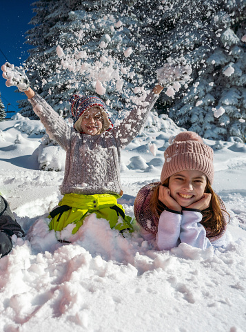 Happy siblings having fun on the snow during winter day on a mountain
