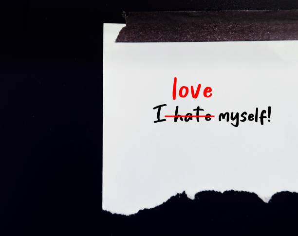 istock Torn paper on black wall with handwritten sentence I HATE MYSELF, crossed off - replaced with I LOVE MYSELF, concept of develop self worth, catch negative inner critic and change to positive affiirmtation 1498607213