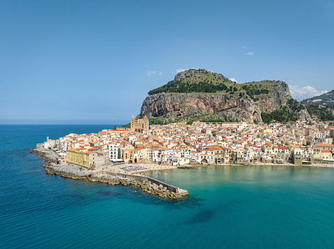 Cefalù City Aerial View over the Mediterranean Sea of North Sicily's Tyrrhenian Coast. Iconic Cefalù Cathedral in the village center and famous outstanding rock La Rocca in the back of Cefalu Old Town. Cefalu, Tyrrhenian Coast, Gibilmanna, Northern Sicily, Sicily Island, Italy, Southern Europe.