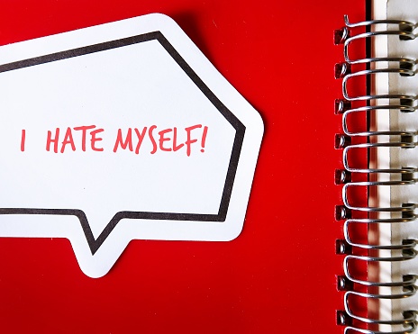 Word sticker on red notebook with text written I HATE MYSELF, concept of self hatred ,negative inner critic which constantly puts down, critical voice compare tell that they are not good enough