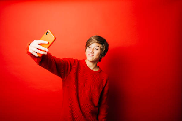 istock Pre-adolescent boy taking a selfie over a red background 1498611658