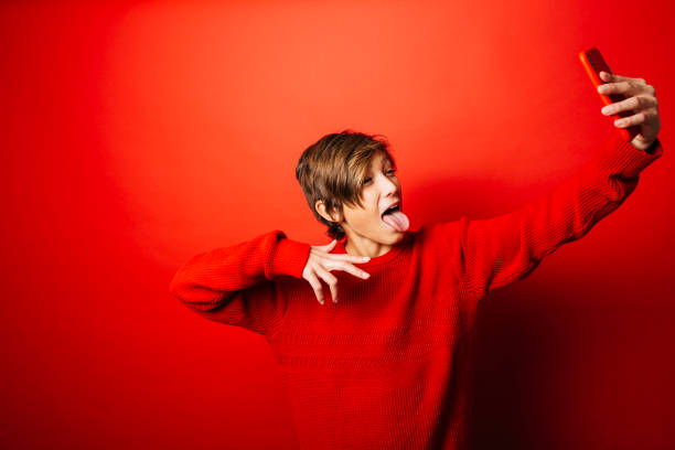 istock Pre-adolescent boy taking a selfie over a red background 1498611660