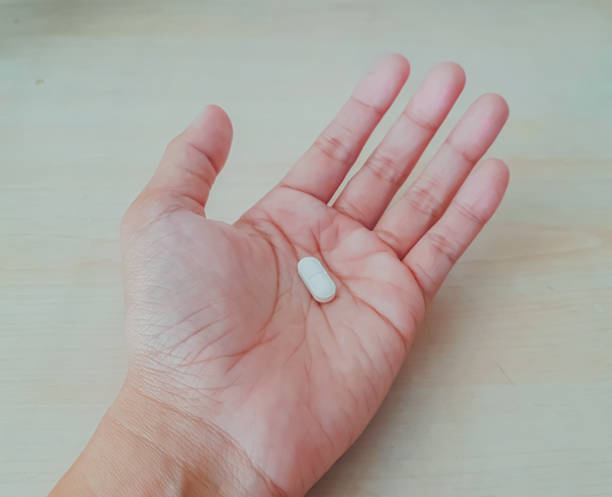 istock white capsule pill on the palm, bacterial infection treatment 1498612394