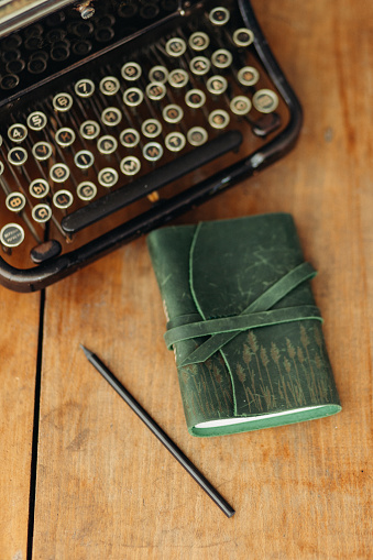 The composition is carefully arranged, with the notebook placed prominently, surrounded by a few well-placed pencils. The typewriter and analog phone add to the retro aesthetic, evoking a sense of nostalgia and classic charm.
