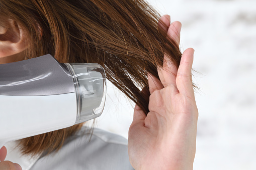 Woman's hand drying hair with hairdryer
