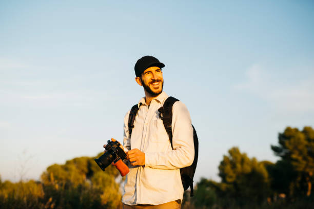 istock Young man at countryside with a digital camera 1498620012