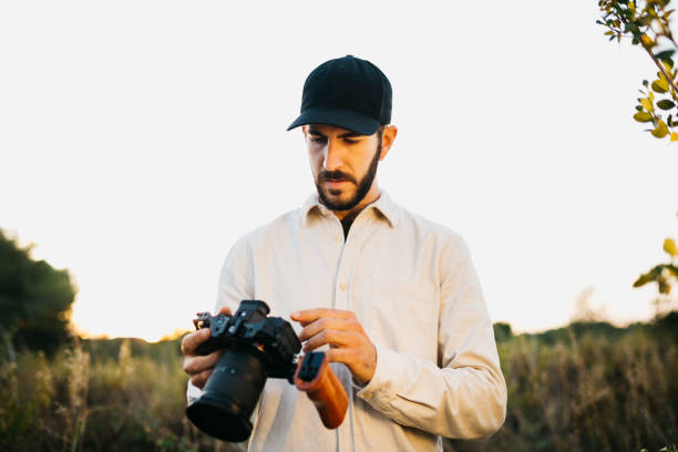 istock Young man with a digital camera at countryside 1498620026