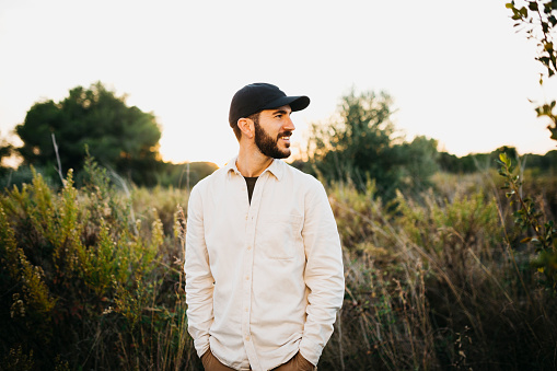 Portrait of a young bearded man wearing a black cap at countryside