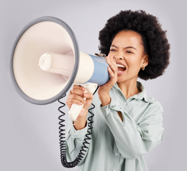 istock Megaphone, protest and black woman shouting in studio isolated on white background with voice. Screaming, angry and person with loudspeaker for human rights, change or justice, announcement or speech 1498620459