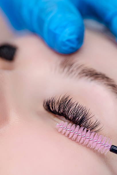 istock Beautician Tattooing Woman's Eyebrows Using Special Equipment During Process of Permanent Make-up Tidying Up Using Brush. 1498620764