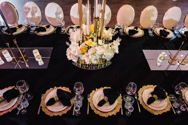 istock Serving, setting table. Wedding set up, dinner reception. Birthday, baptism, event. Festive tables with flowers, candles. Luxury golden rich decor. Plate decorated napkin, cutlery, glasses. Top view. 1498624299