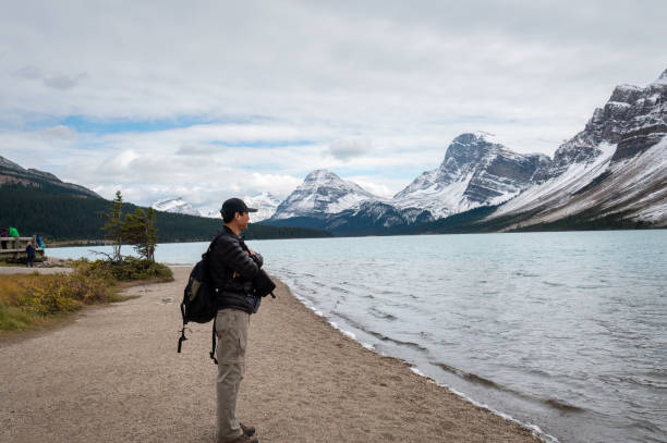 istock Tourist looking at Athabasca River with snow-capped mountains in the background. Jasper National Park, Alberta, Canada. 1498627056
