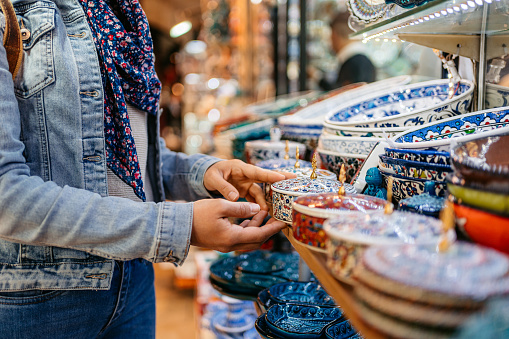 Young woman looking porcelain dishes at the Grand Bazaar In Kapali Carsi in Istanbul, Turkey. Close-up.