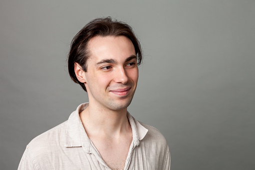 Studio portrait of a young white men in a beige shirt against a gray background