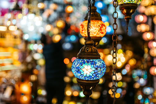 Middle Eastern lambas of different colors and sizes are hanging in the bazaar. Bright traditional Arabic and Turkish lanterns made of metal and glass, inlaid with mosaic details of different colors.