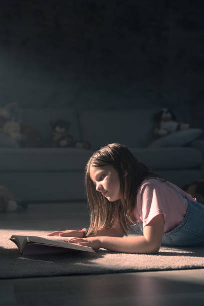 istock Child reading a book lying on the floor 1498630739