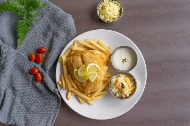 A plate of traditional fish and chips, accompanied by a bowl of creamy ranch dressing