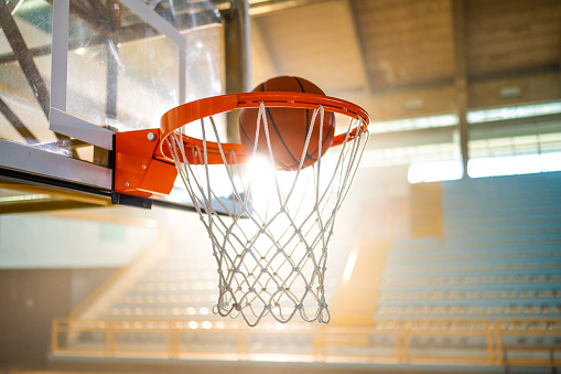 Close-up of basketball reaching in hoop at stadium.