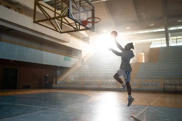Basketball player throwing ball in hoop on sports court during practice.