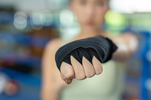 Close up of the fist of an asian female boxer getting ready for boxing exercise in a boxing ring in a gym