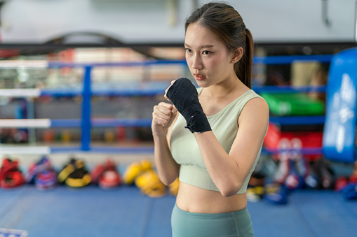 Asian female boxer getting ready for boxing exercise in a boxing ring in a gym