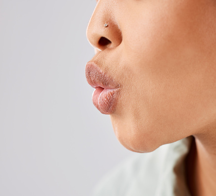 Pout, lips and woman face whistle with her mouth or kiss with lipstick or gloss isolated in a white studio background. Flirting, care and natural lip of a female person showing love, care and romance