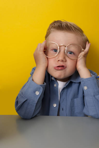 istock A fair-haired boy in glasses grimaces on a yellow background copy space 1498640249