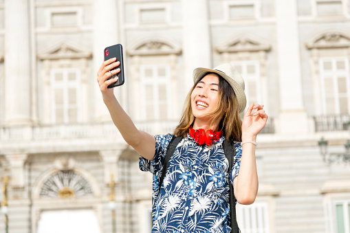 Young Asian tourist exploring city, making a video call on mobile phone