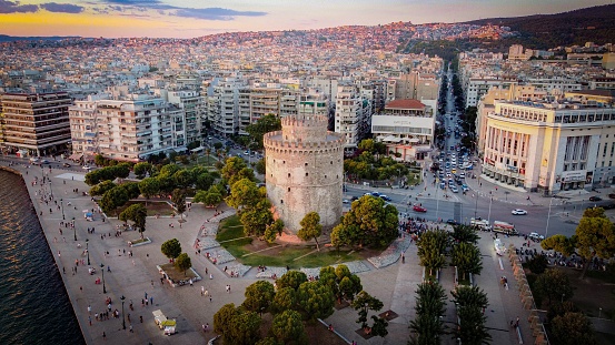 Thessaloniki, Greece – February 10, 2023: An aerial view of the White Tower Of Thessaloniki in Greece, featuring  lush green trees and bustling urban cityscape