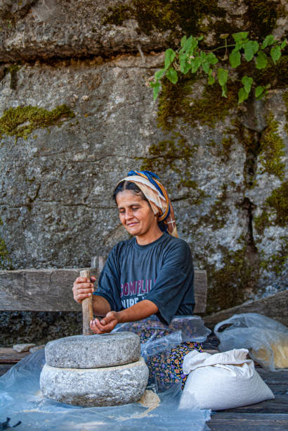 Turkey, Antalya - August 31, 2006: Turkish woman grinding wheat with the traditional method in the Taurus Mountains. Köprülü Canyon National Park
