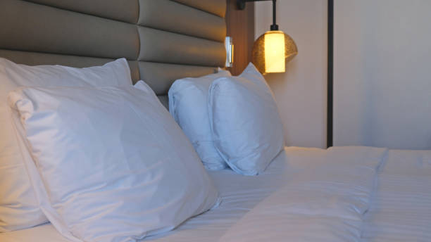 istock Close-up fragment of bedroom with empty bedside table, turn on reading lamp and a socket in modern interior​ design home or hotel. Soft pillow and blanket, stylish comfortable furniture. 1498644428